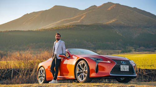 Homme posé sur une Voiture décapotable de luxe Lexus devant une montagne