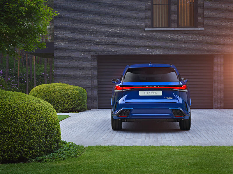 Voiture hybride Lexus RX garée devant un garage de maison