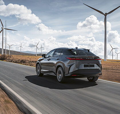 Voiture électrique Lexus roulant sur une route bordée d'éoliennes