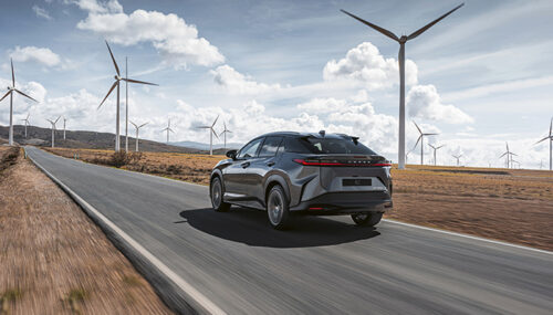 Voiture électrique Lexus roulant sur une route bordée d'éoliennes