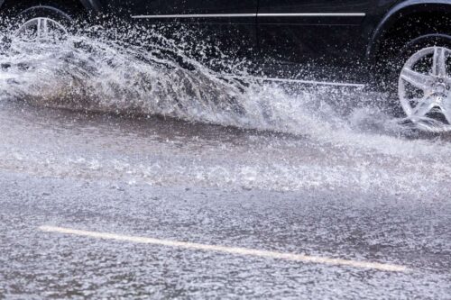 Voiture qui roule sur une route pleine d'eau par temps de pluie