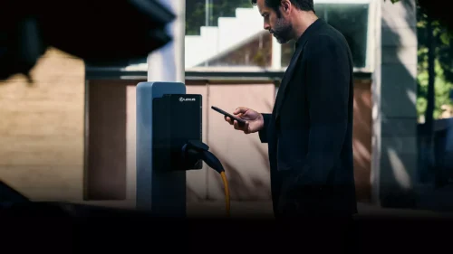 Homme debout activant la recharge de son véhicule électrique depuis son smartphone